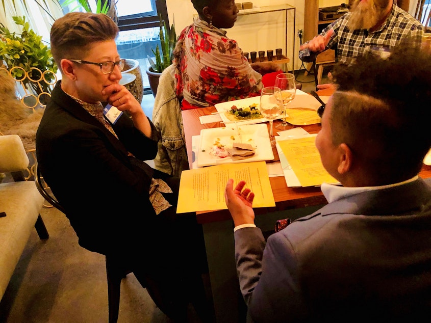 caption: KUOW Curiosity Club members Keri Zierler (left) and Mellina White Cusack talk during Queeriosity Club at The Cloud Room in Seattle. KUOW producer Adwoa Gyimah-Brempong talks with Club member Jeffrey Howard in the background. June 7, 2019.  