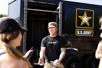 caption: Staff Sgt. Joshua Spearman talks to fairgoers at the Army recruitment tent at the Minnesota State Fair in Falcon Heights, Minn., on August 31.