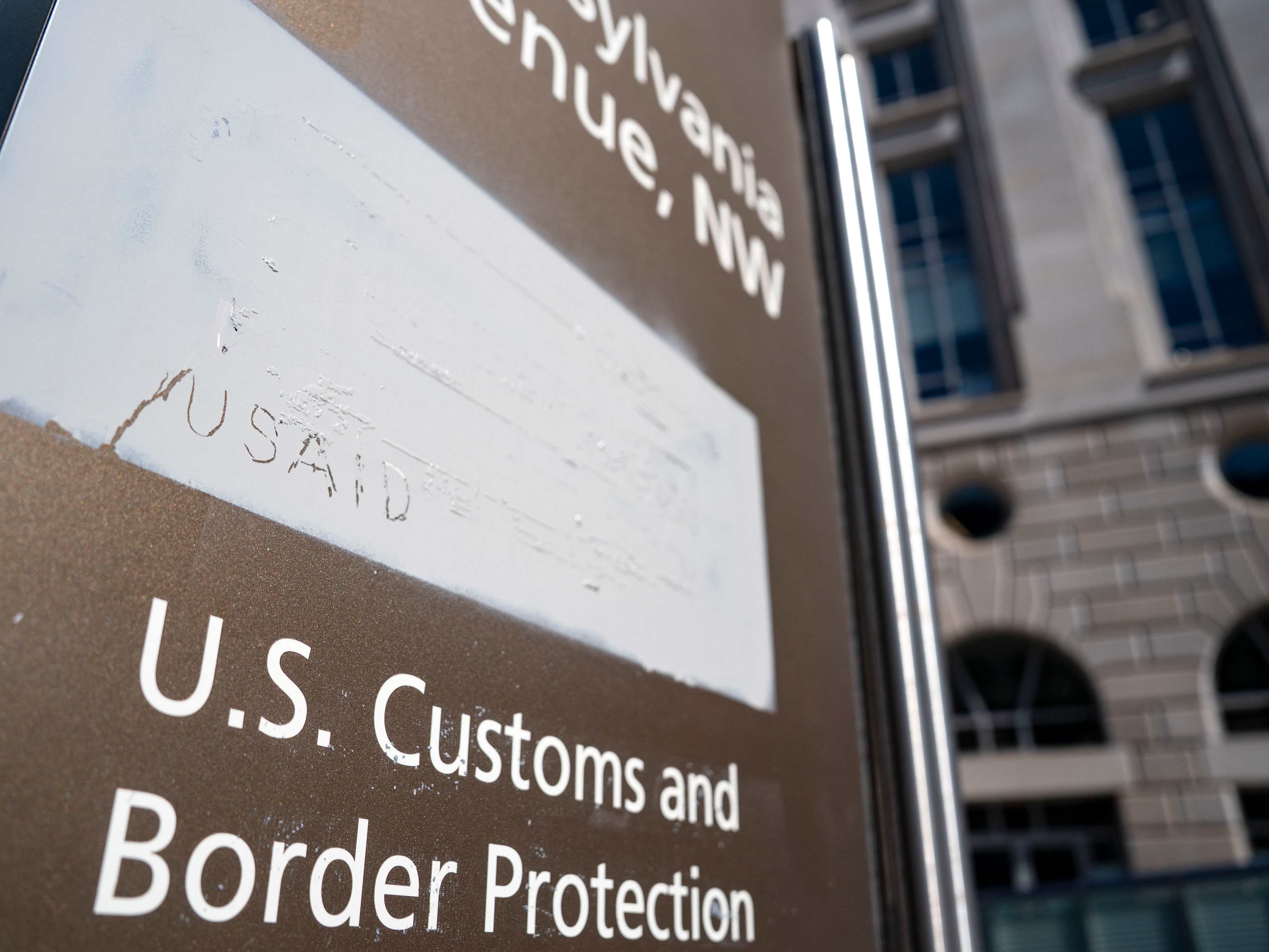 caption: "USAID" is etched onto a covering where signage used to be at the U.S. Agency for International Development headquarters in Washington, D.C.