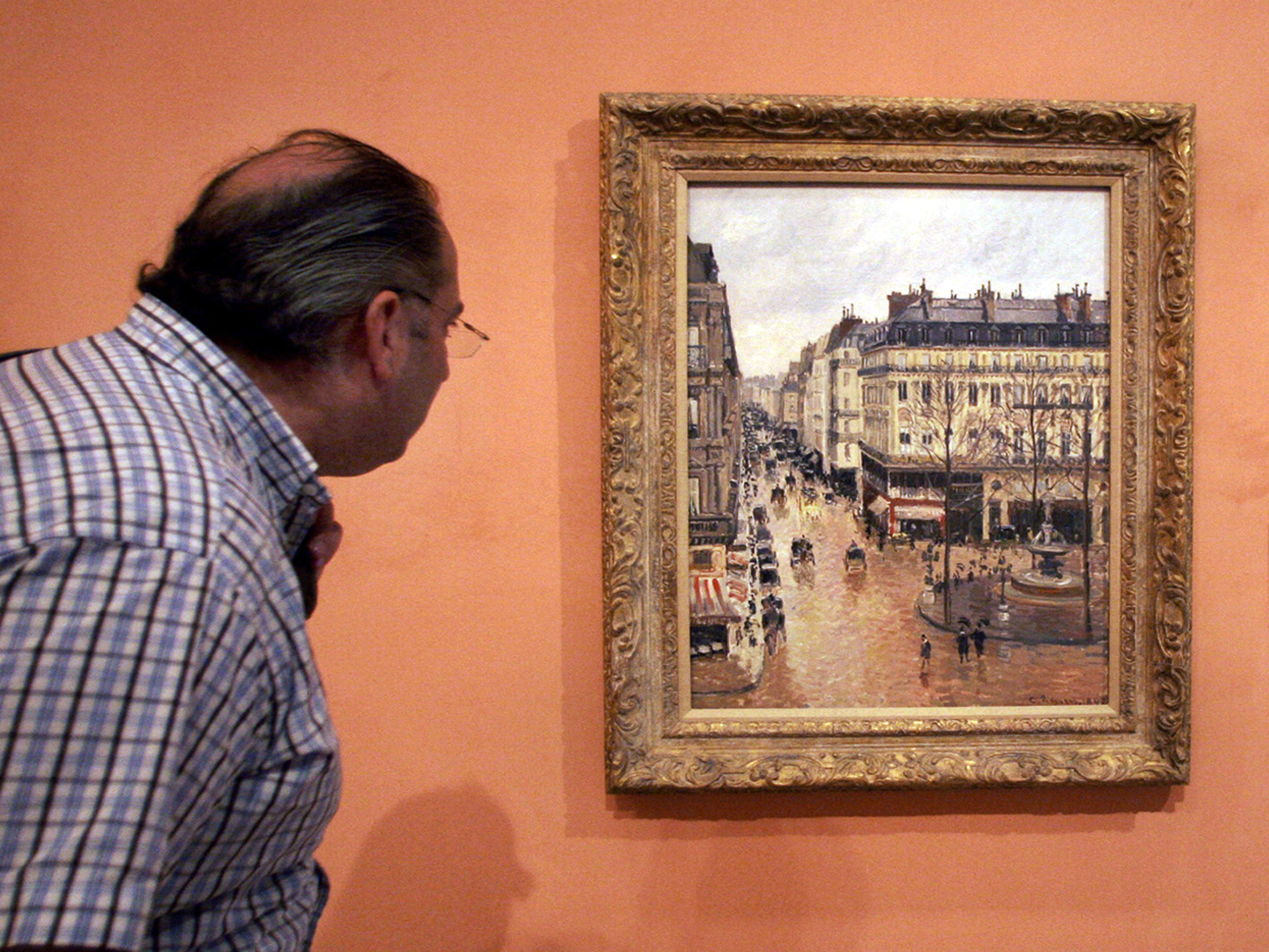 caption: A visitor in 2005 views the impressionist painting called <em>Rue St.-Honore, Apres-Midi, Effet de Pluie,</em> painted in 1897 by Camille Pissarro, on display in the Thyssen-Bornemisza Museum in Madrid.