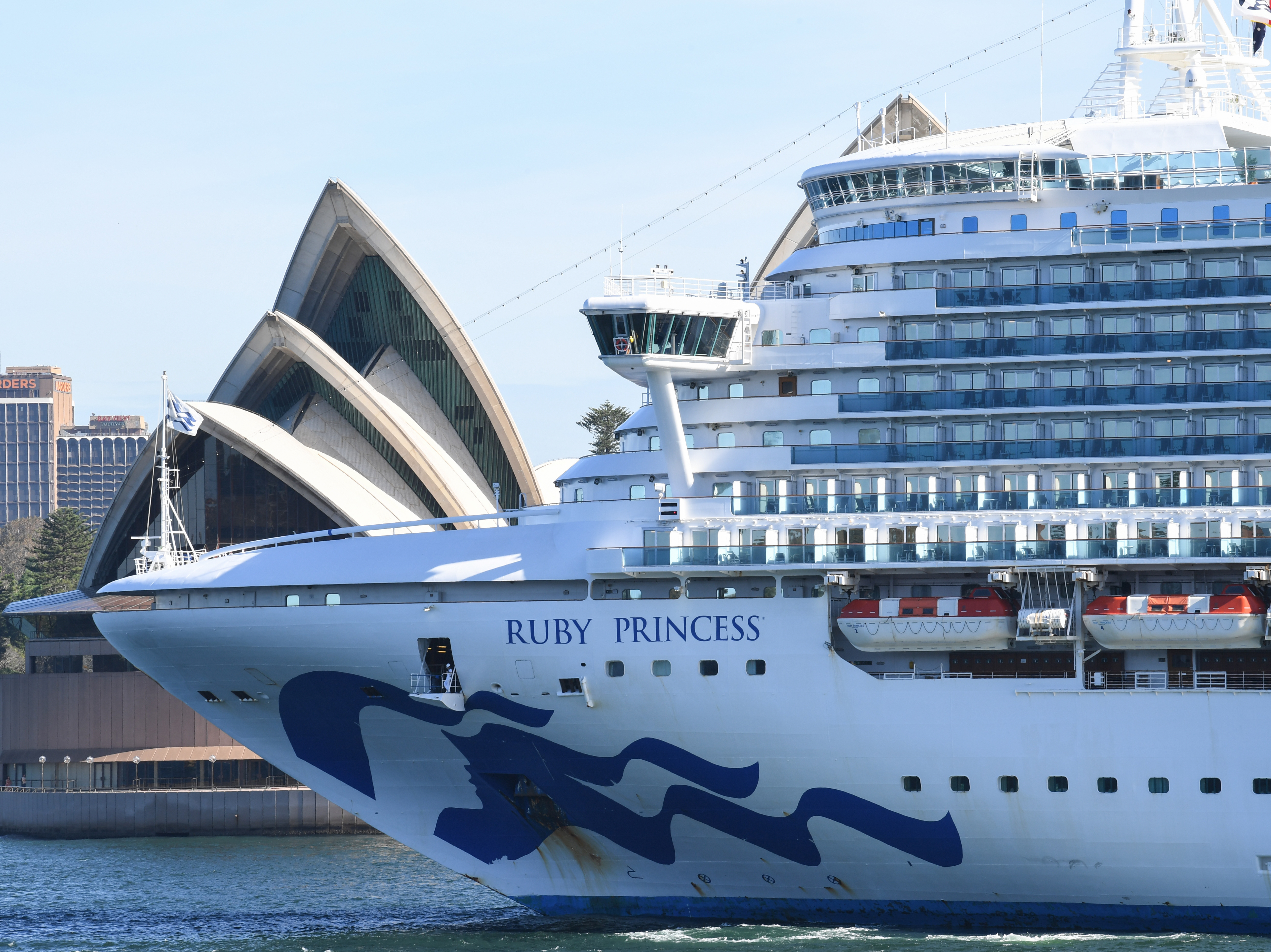 caption: Ruby Princess departs Sydney Harbour on Thursday. Three passengers and one crew member aboard the vessel have tested positive for the novel coronavirus.