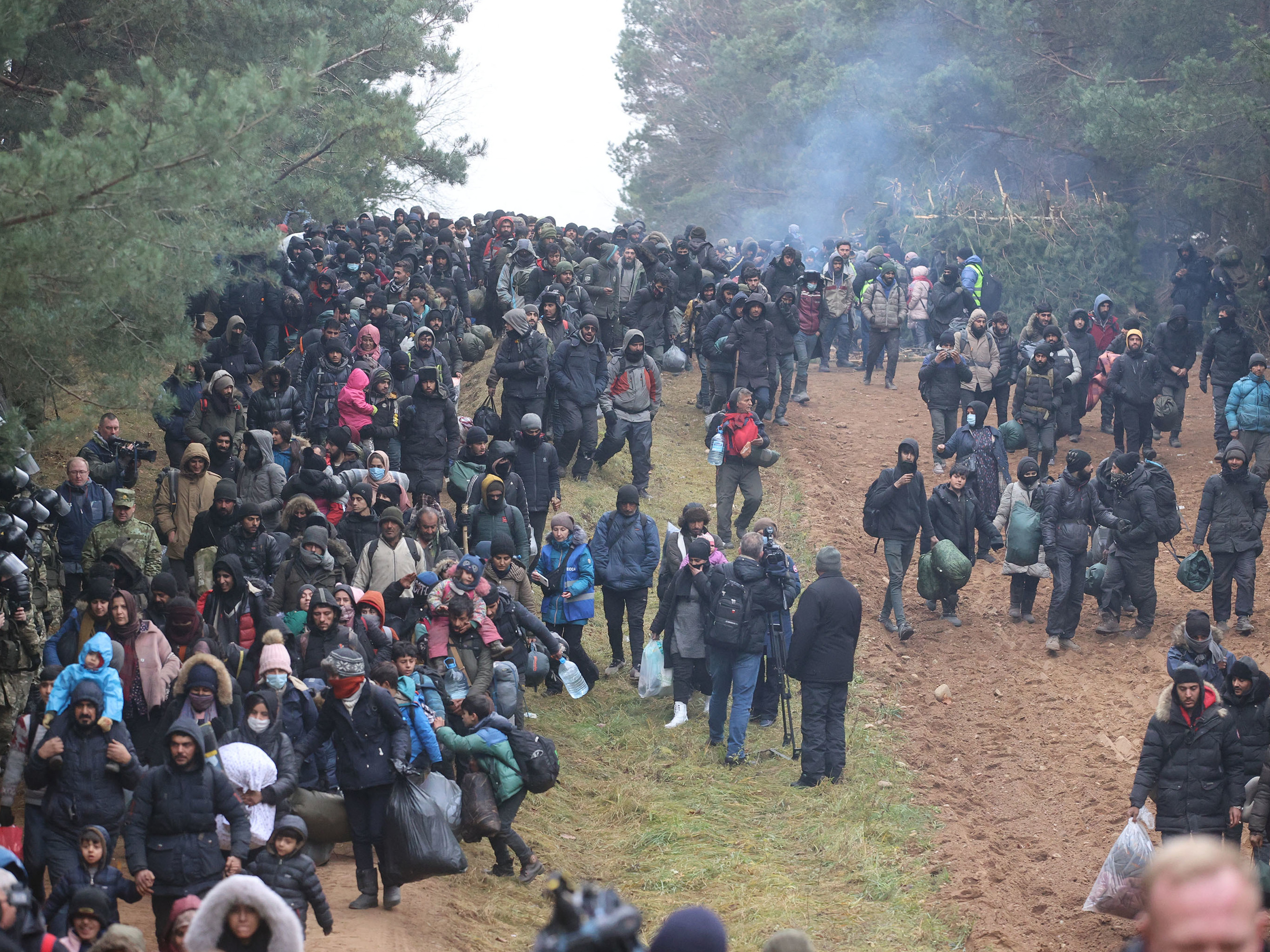 caption: Migrants head toward a border checkpoint on the Belarusian-Polish border on Nov. 15, 2021.