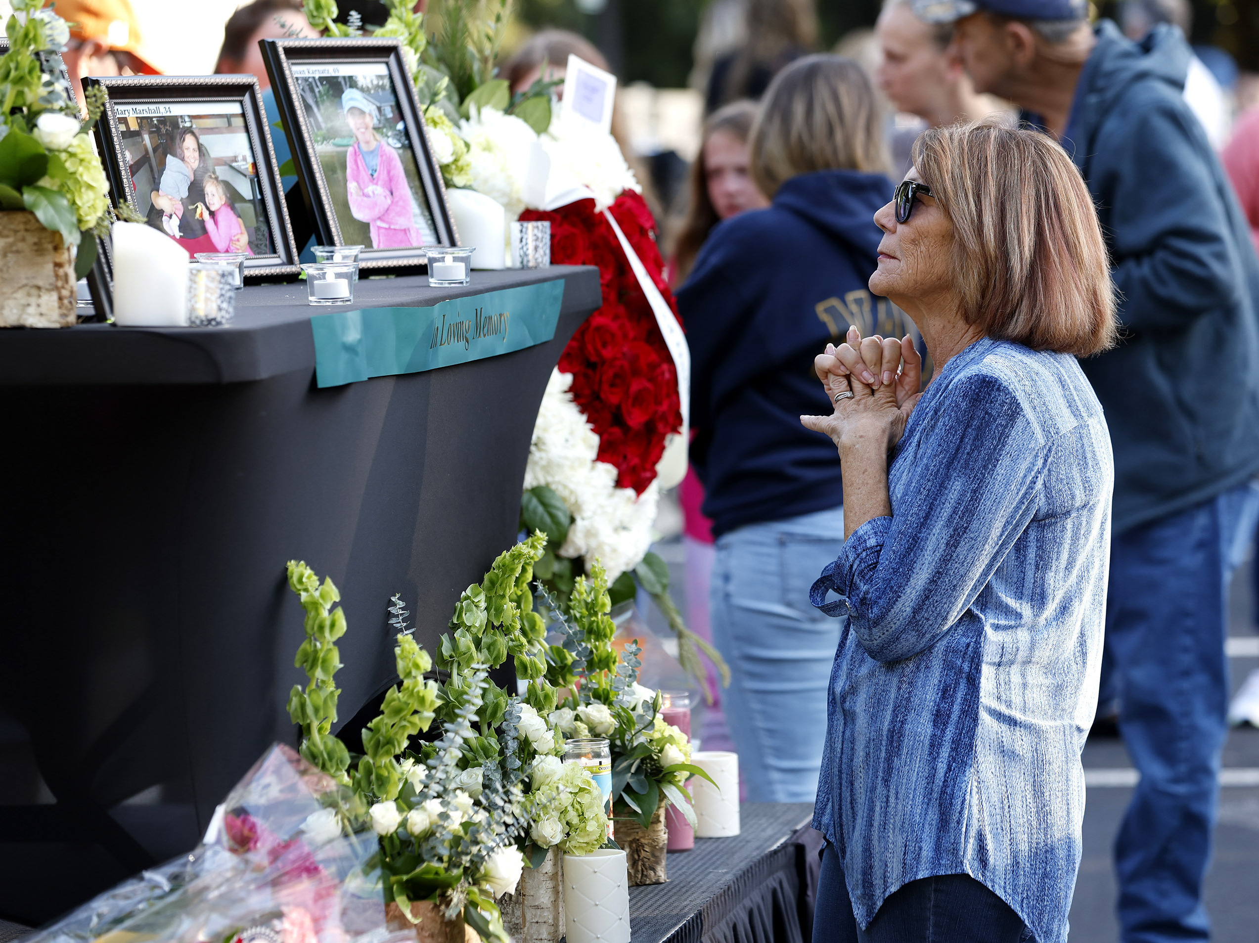 caption: A woman stands before a photo of Raleigh shooting victim Susan Karnatz at a makeshift memorial.