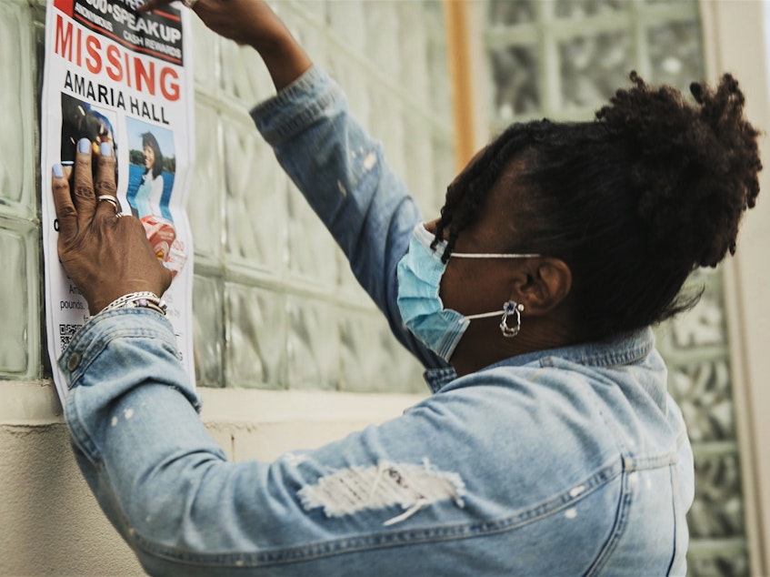 caption: A community member posts flyers for Amaria Hall.