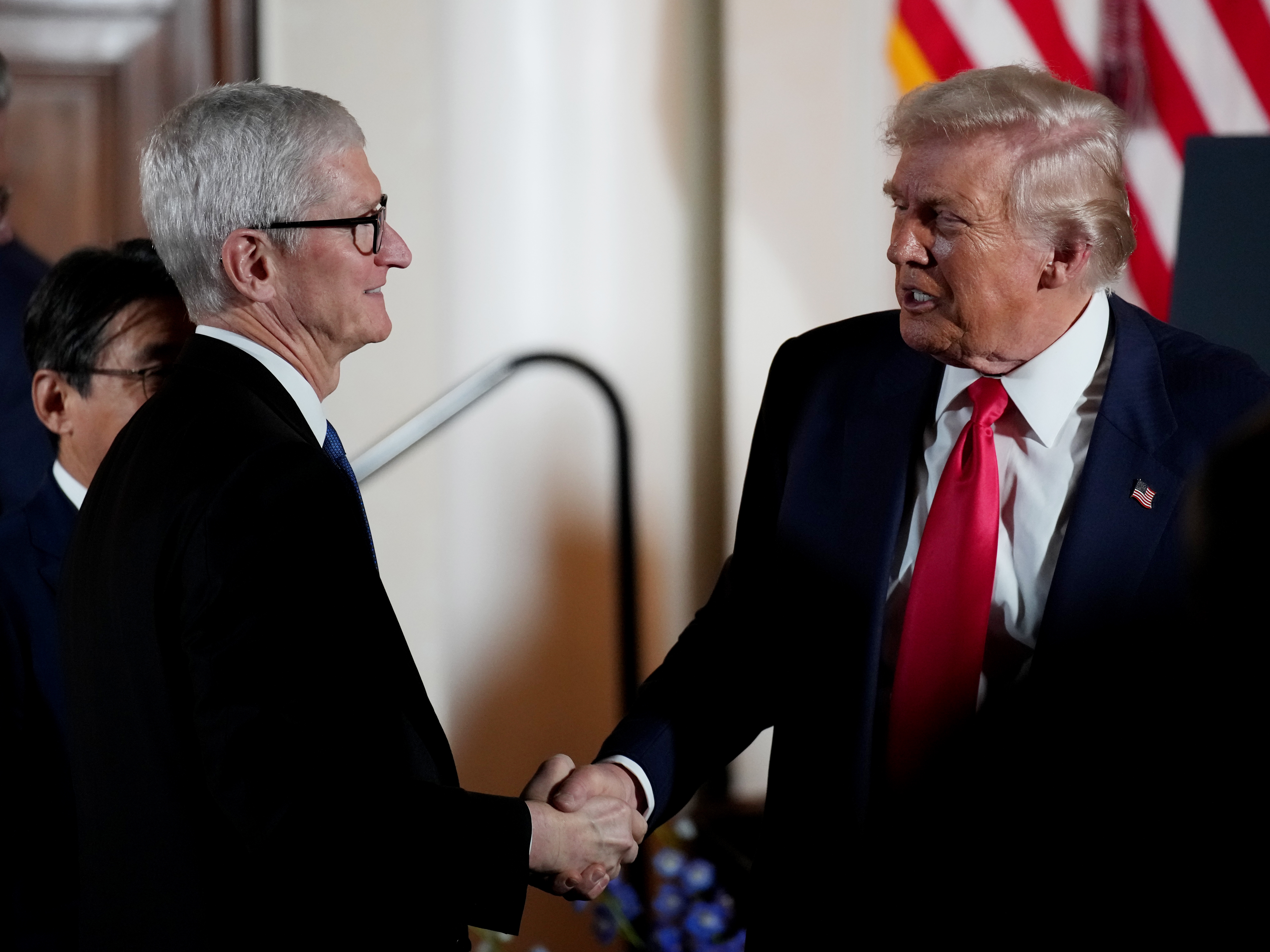 caption: President Trump shakes hands with Apple CEO Tim Cook during a meeting with business leaders in Tokyo in October. Cook is among the CEOs who have personally courted Trump in the past year and whose companies' products have escaped the worst of Trump's tariffs.