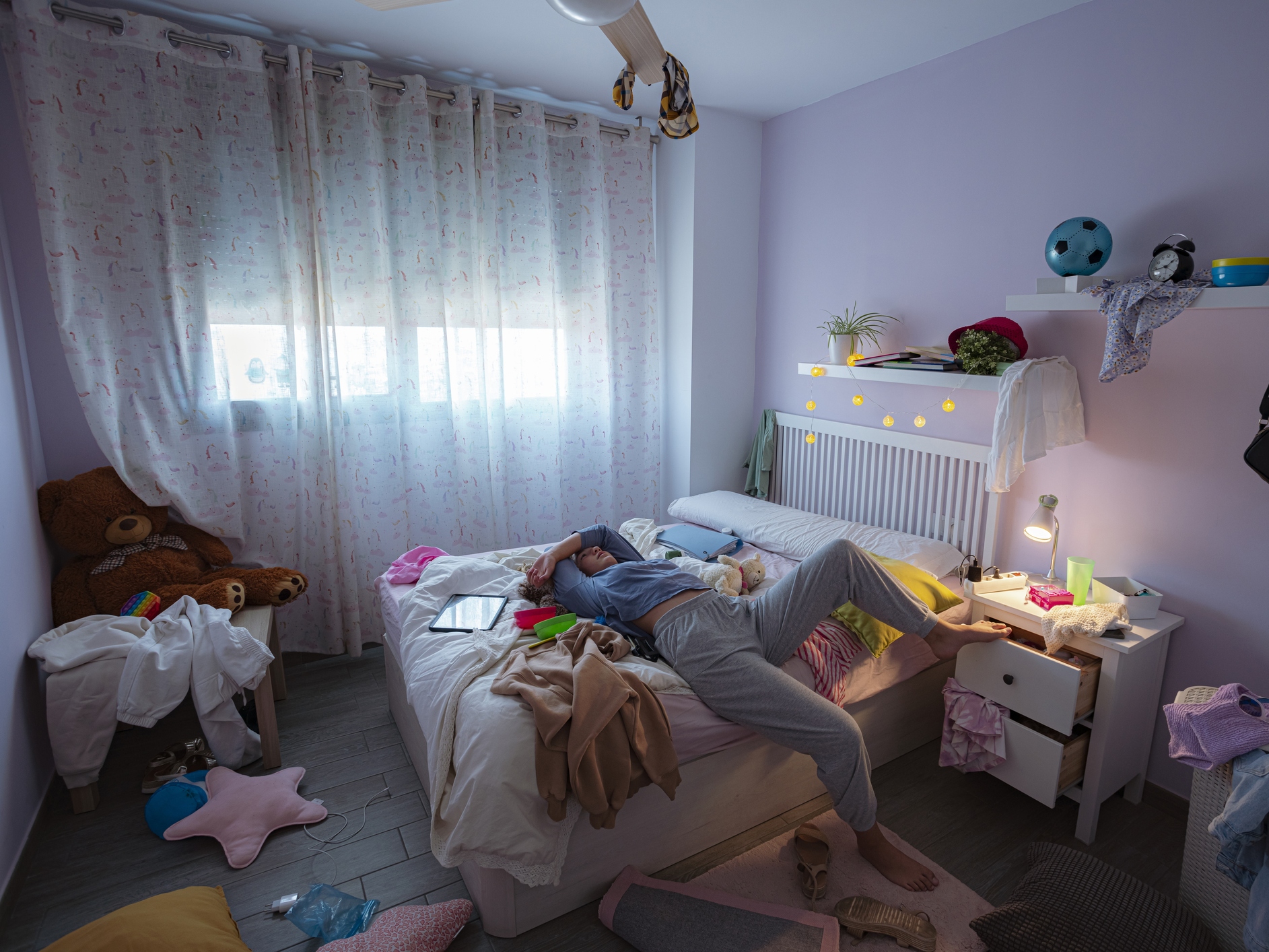 Lazy teenager laying in bed in her messy room