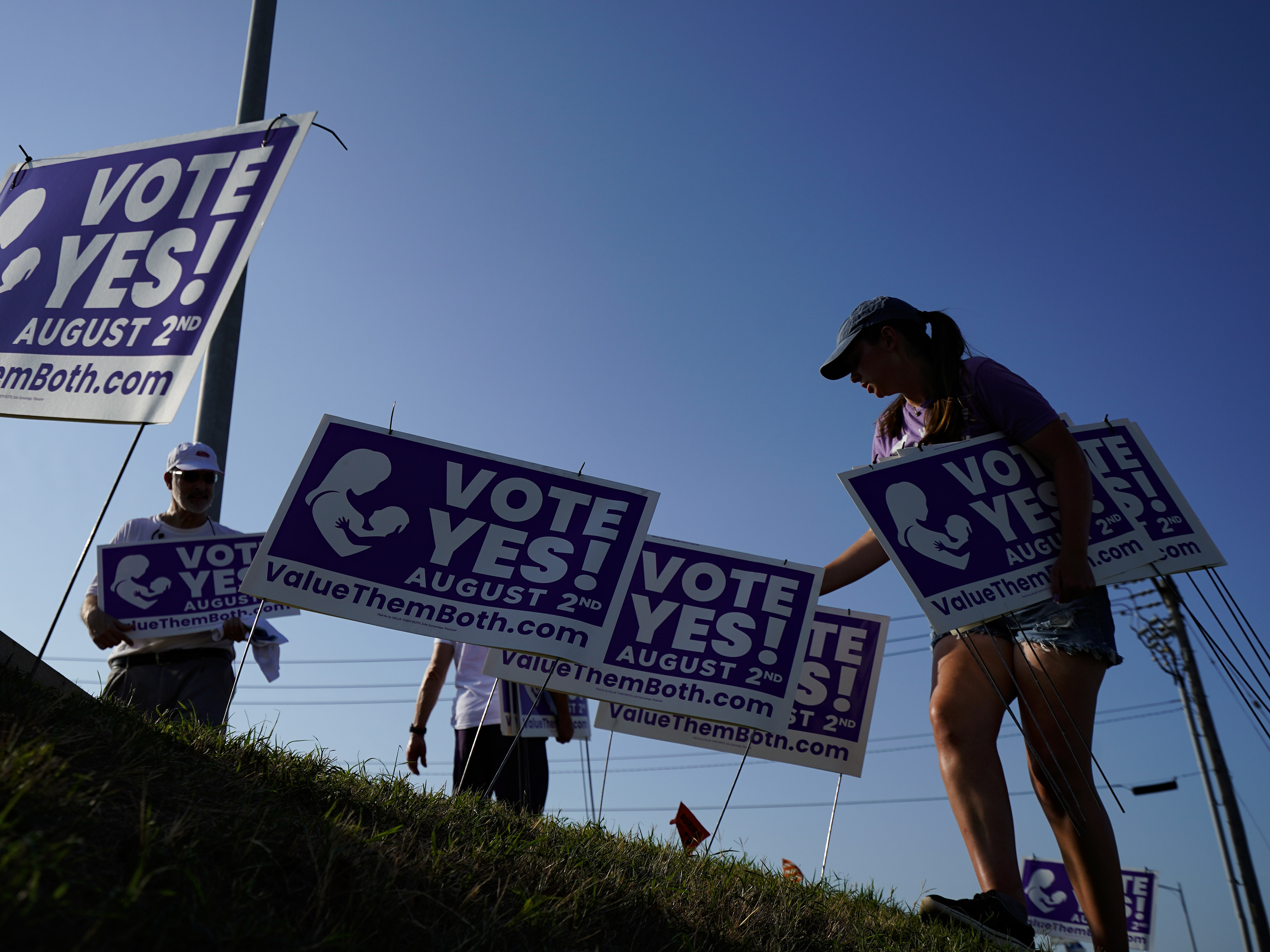 caption: Supporters of a constitutional amendment about abortion in Kansas remove signs ahead of Tuesday's vote.