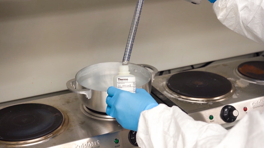 caption: Researcher with Hazardous Waste Management Program tests an aluminum cookpot under simulated cooking conditions to measure lead exposure. 
