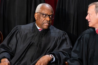caption: Associate Justice Clarence Thomas, left, talks to Chief Justice John Roberts during the formal group photograph at the Supreme Court in Washington, D.C., on Oct. 7, 2022.