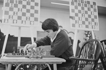 caption: Georgian chess champion Nona Gaprindashvili plays at the International Chess Congress in London on Dec. 30, 1964. She is suing Netflix for defamation and invasion of privacy over its series <em>The Queen's Gambit.</em>