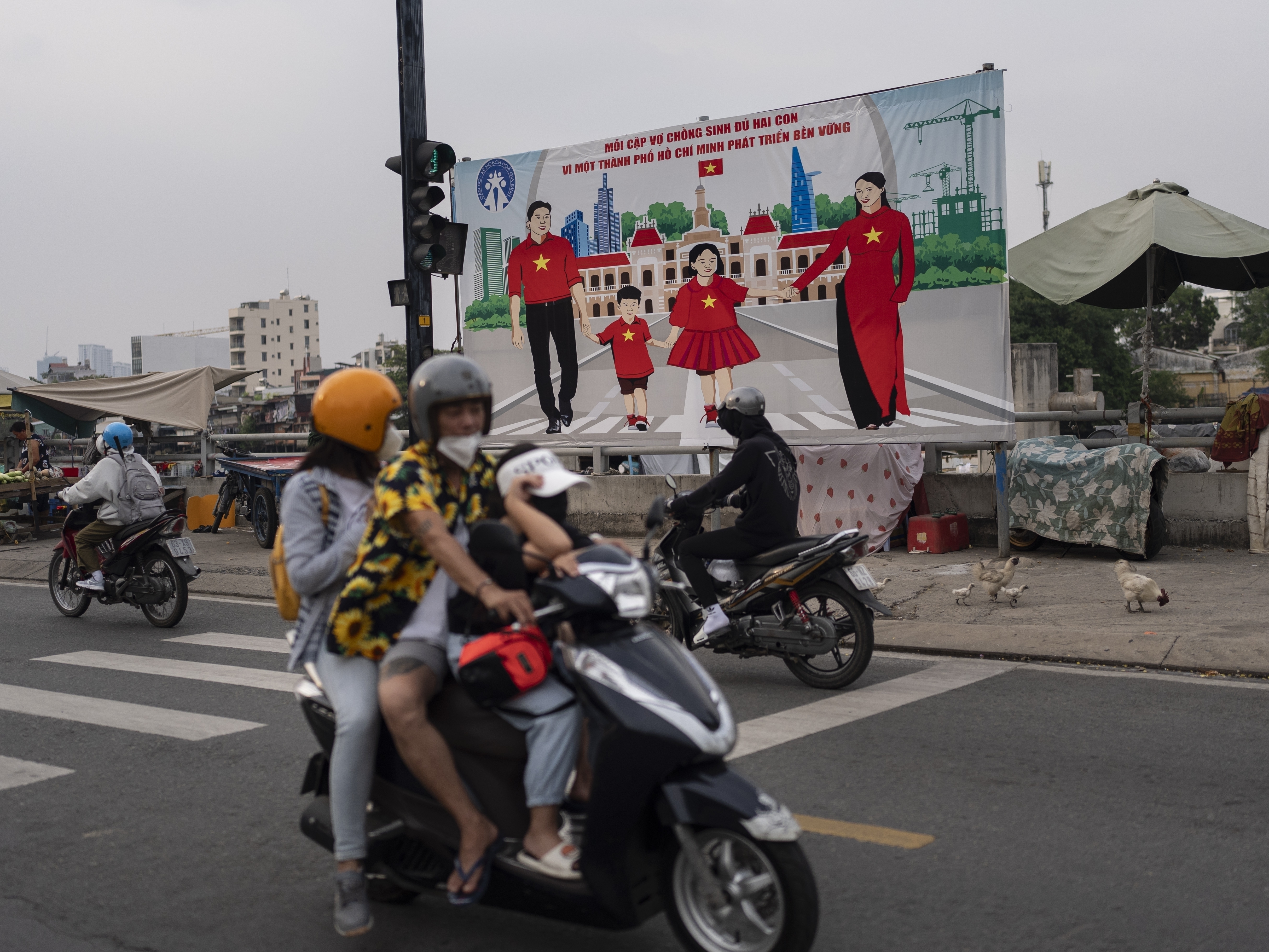 caption: A billboard campaigning for each family to have two children hangs above a street in Ho Chi Minh City, Vietnam, Jan. 14, 2024.