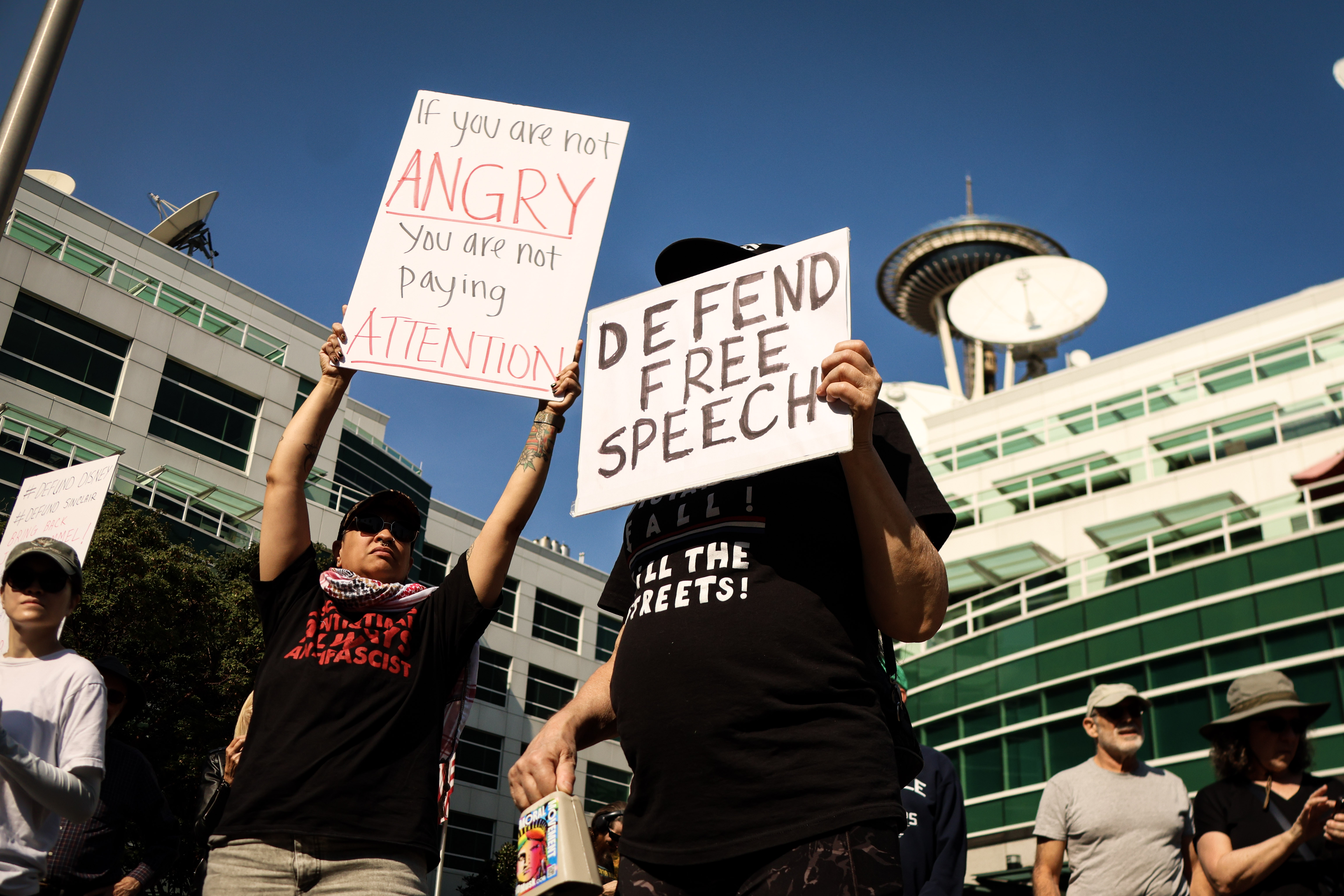 caption: Several people gather at Komo Plaza in downtown Seattle to protest Sinclair&#39;s decision not to broadcast the Jimmy Kimmel Show. September 23, 2025.