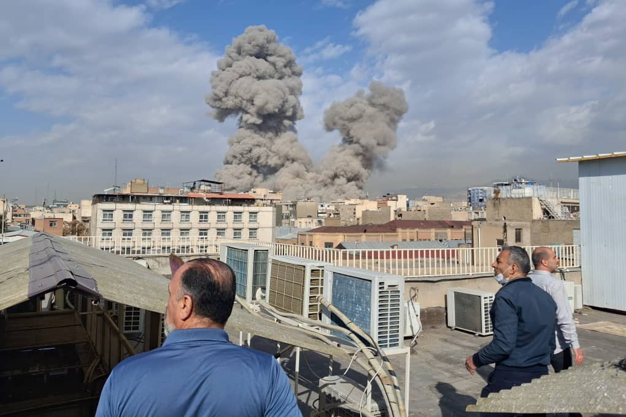 caption: People watch as smoke rises on the skyline after an explosion in Tehran, Iran, Saturday, Feb. 28, 2026.

