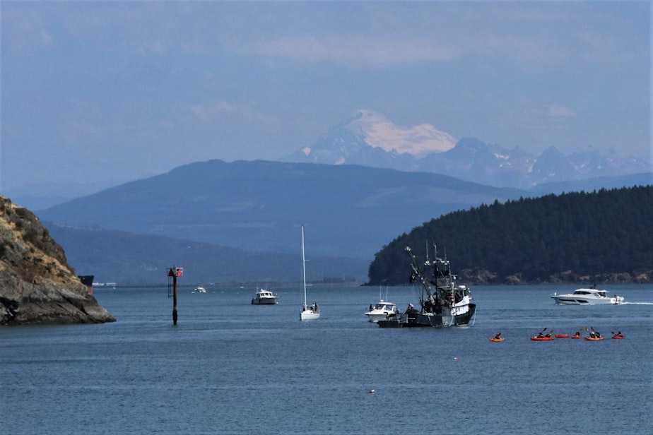 caption: The Aleutian Isle prepares to head out to sea after its support skiff towed it away from Cap Sante Marina in Anacortes on Aug. 12, 2022, with Mount Baker in the background.