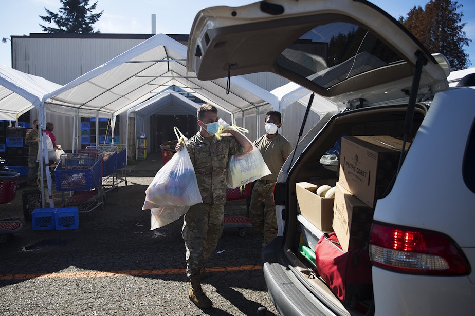 caption: Spc. Erik Jones, left, and Spc. Andre Bhatt with the Washington National Guard load bags and boxes of food into the back of a vehicle on Tuesday, September 22, 2020, at the Tukwila Pantry Food Bank on South 140th Street in Tukwila.