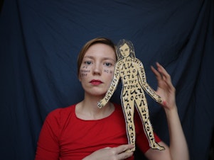 caption: A self-portrait of Darya Apakhonchich, with the writing on her face and a figure of a woman saying: "Not only a body but a person, person, person, person, person." She made the photo in support of Russian artist and LGBTQ activist Yulia Tsvetkova, who faces criminal charges for spreading pornography through her art.