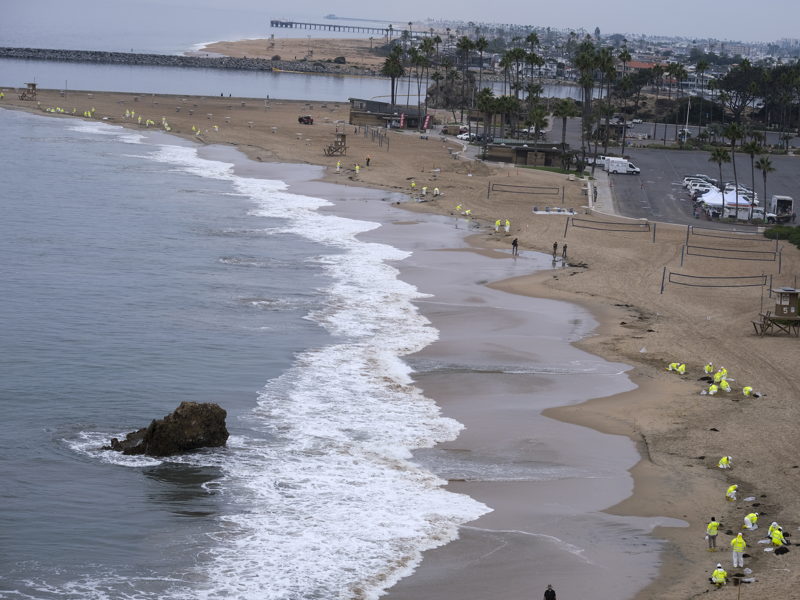 caption: Workers in protective suits clean the contaminated beach in Corona Del Mar on Oct. 7 after an oil spill in Newport Beach, Calif.