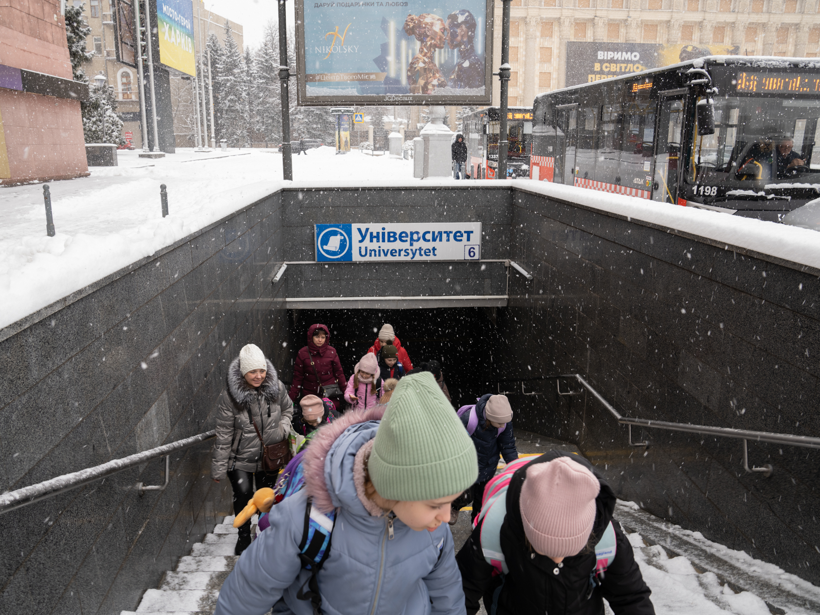 caption: Students leave the underground school built in a Kharkiv subway station to board a bus home.