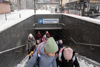 caption: Students leave the underground school built in a Kharkiv subway station to board a bus home.