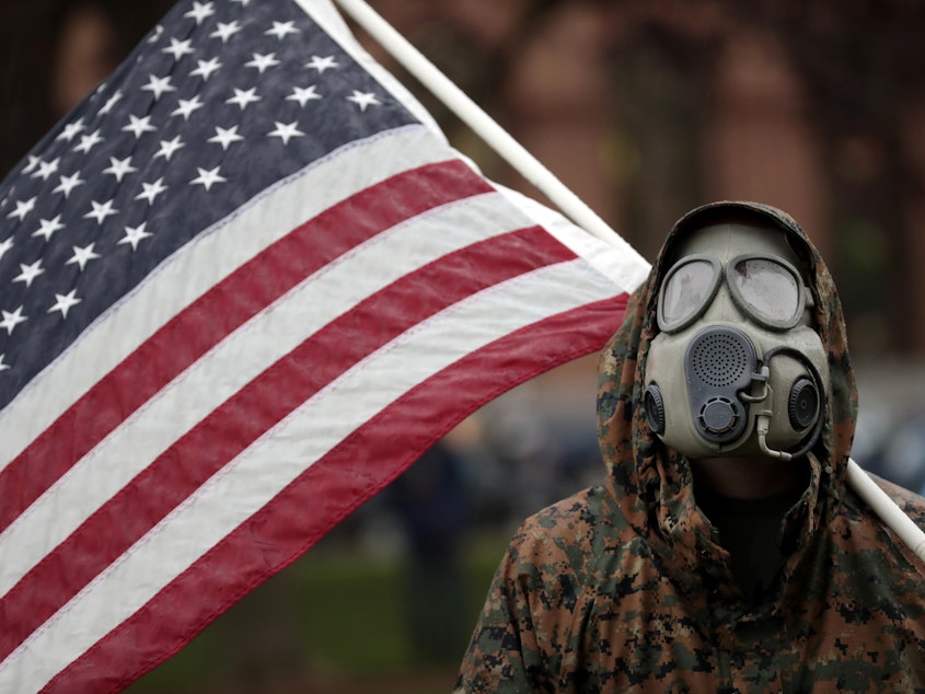 caption: A protester attends a demonstration over Michigan's coronavirus restrictions on Thursday at the state Capitol in Lansing.