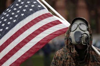 caption: A protester attends a demonstration over Michigan's coronavirus restrictions on Thursday at the state Capitol in Lansing.