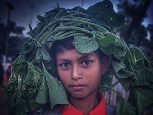 caption: Arfat Ahmed, age 10, photographed on Nov. 8, 2022 as he returns to his family's dwelling with gourd leaves to cook for dinner. This is one of the photos by the four Rohingya photographers honored for drawing attention to the plight of what the U.N. has called the "world's most persecuted minority."