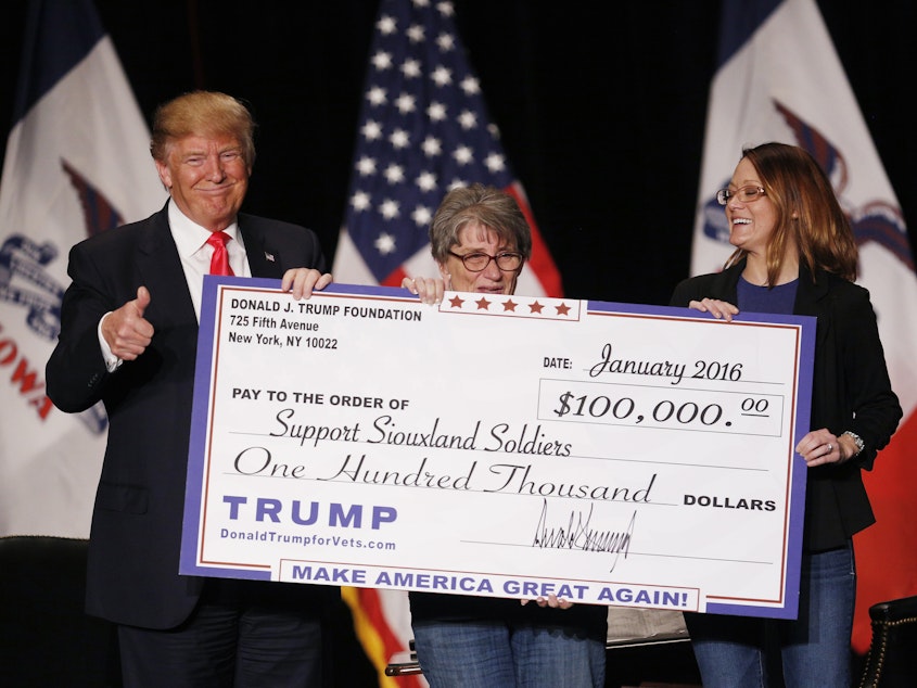 caption: Donald Trump during a January 2016 campaign event awarding a $100,000 check to a veterans charity in Sioux City, Iowa. Trump's use of his personal foundation during the campaign raised legal questions about the foundation's activities.