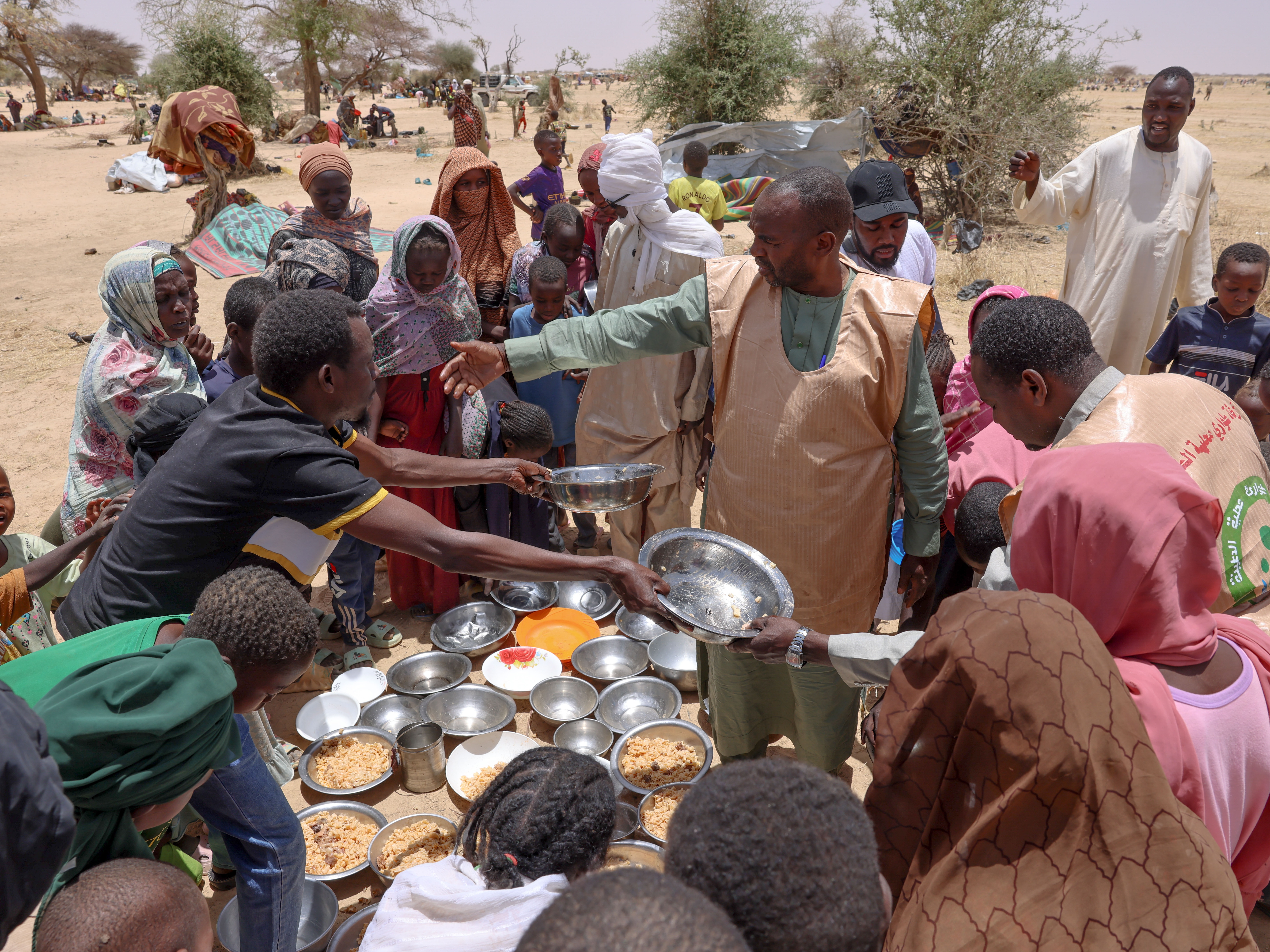 caption: Volunteers from the Sudan Emergency Response Rooms hand out food to families displaced by the country's civil war.