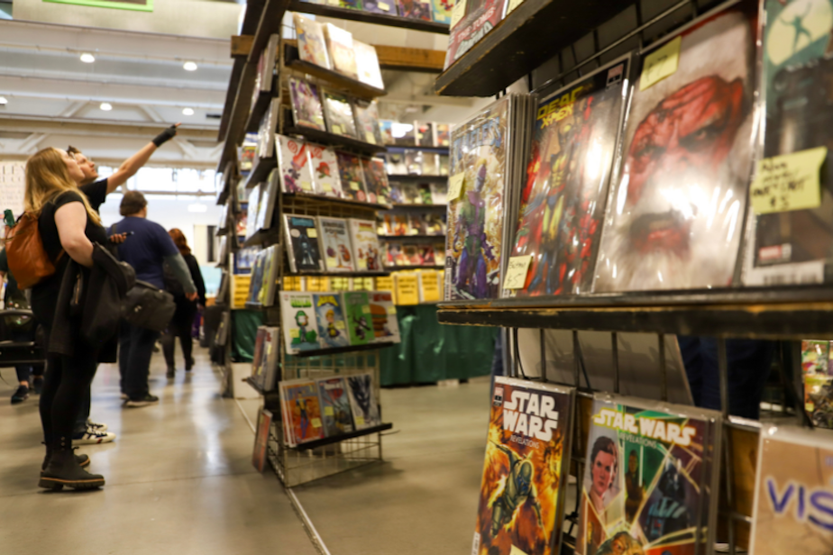caption: KUOW's Dyer Oxley and Katie Campbell browse a comic book booth at the 2024 Emerald City Comic Con at the Seattle Convention Center.