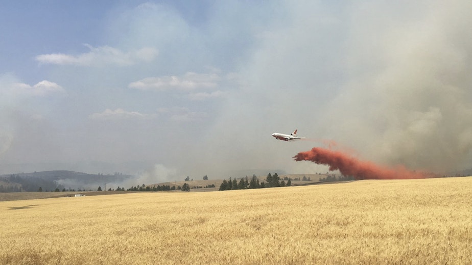 caption: In this photo released by The Eastern Area Incident Management Team, a Very Large Air Tanker (VLAT) drops retardant on a wheat field as crews continue to battle a wildfire in eastern Washington state Sunday, Aug. 5, 2018.