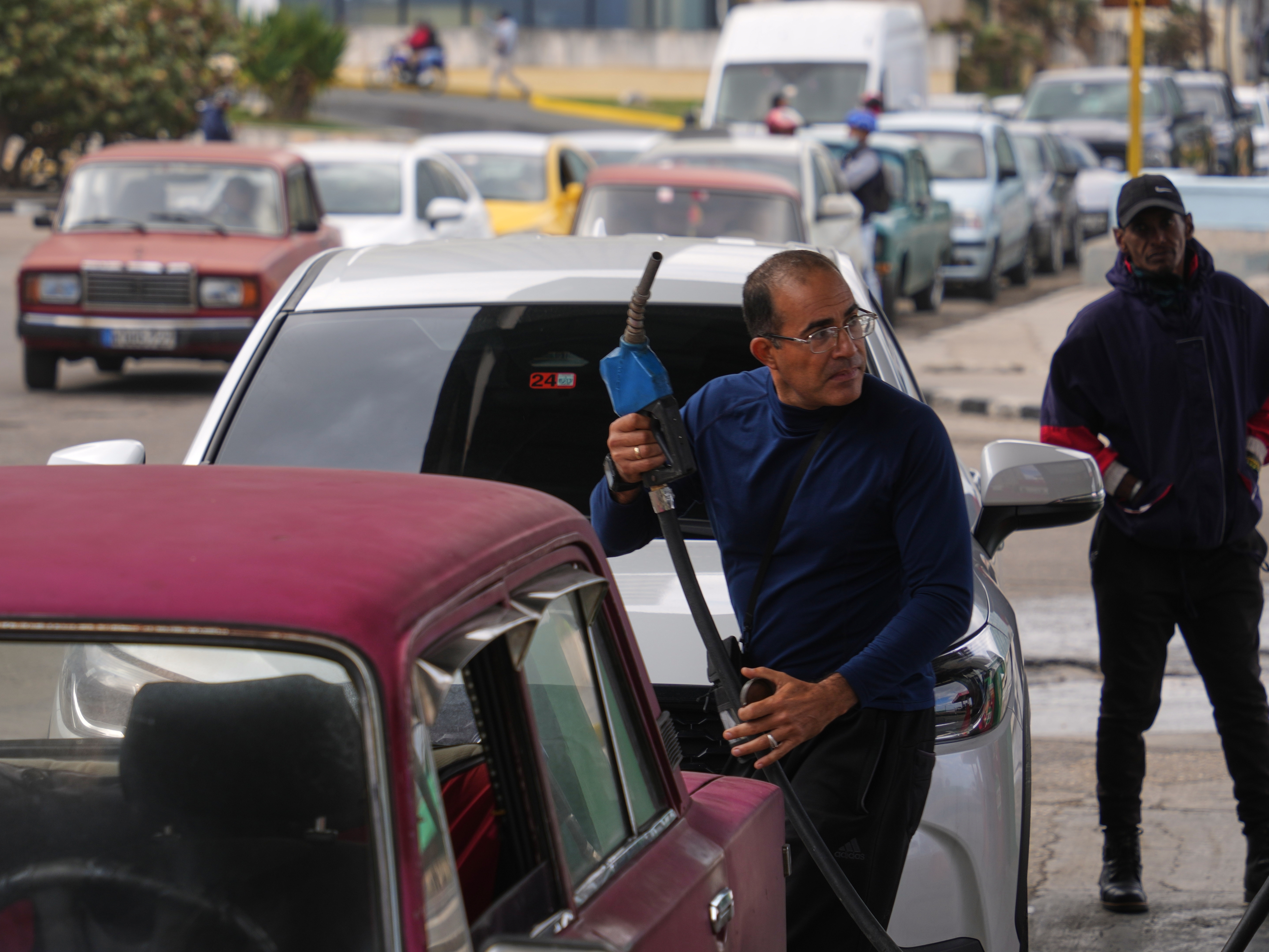 caption: A driver refuels others wait in a long line behind to fill up at a gas station in Havana, Cuba, Tuesday, Jan. 27, 2026.