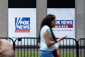 caption: A man who was at the Jan. 6 attack on the U.S. Capitol has sued Fox News for defamation. Here, a woman walks by the Fox News headquarters in New York in April.