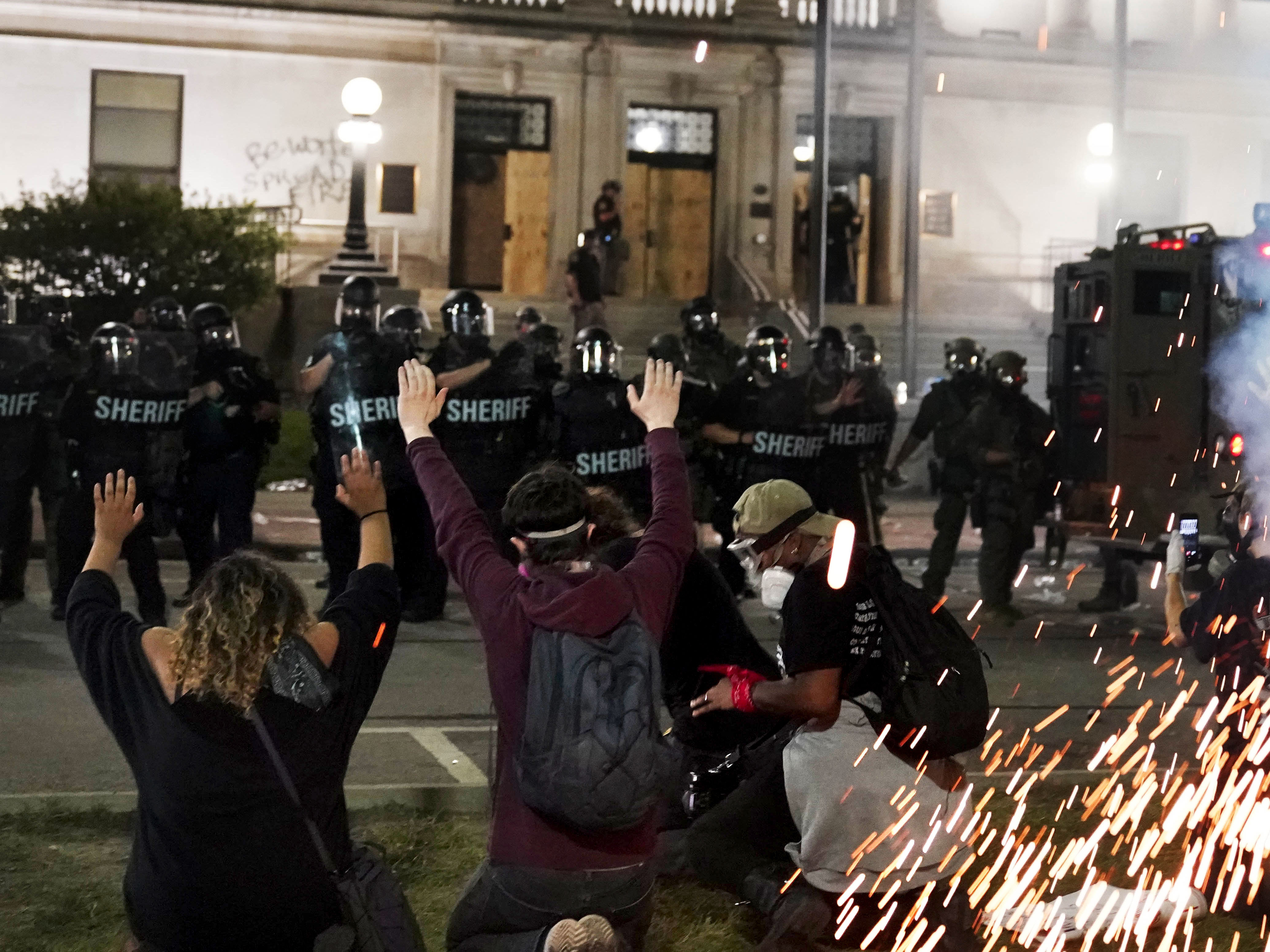 caption: Police attempt to push back protesters outside the Kenosha County Courthouse late Monday. Protesters converged during a second night of clashes after the police shooting of Jacob Blake.