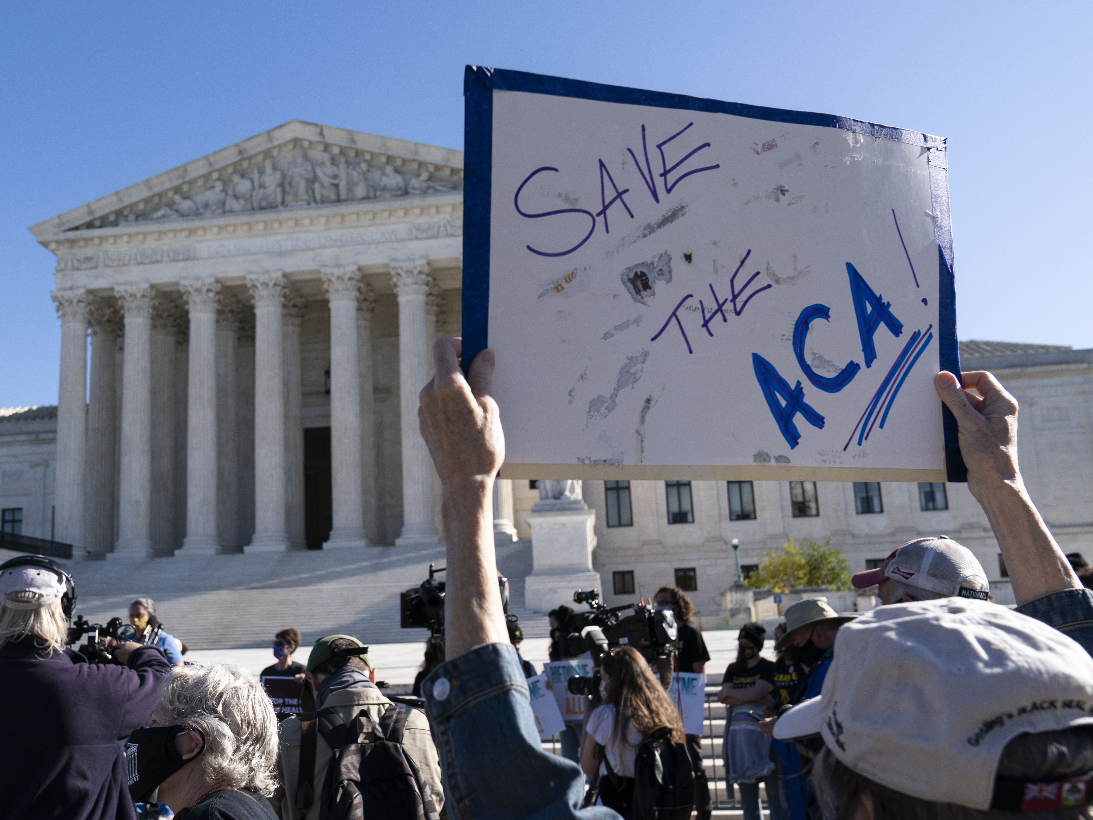 caption: A demonstrator holds a sign in front of the U.S. Supreme Court, which heard arguments over the Affordable Care Act Tuesday.