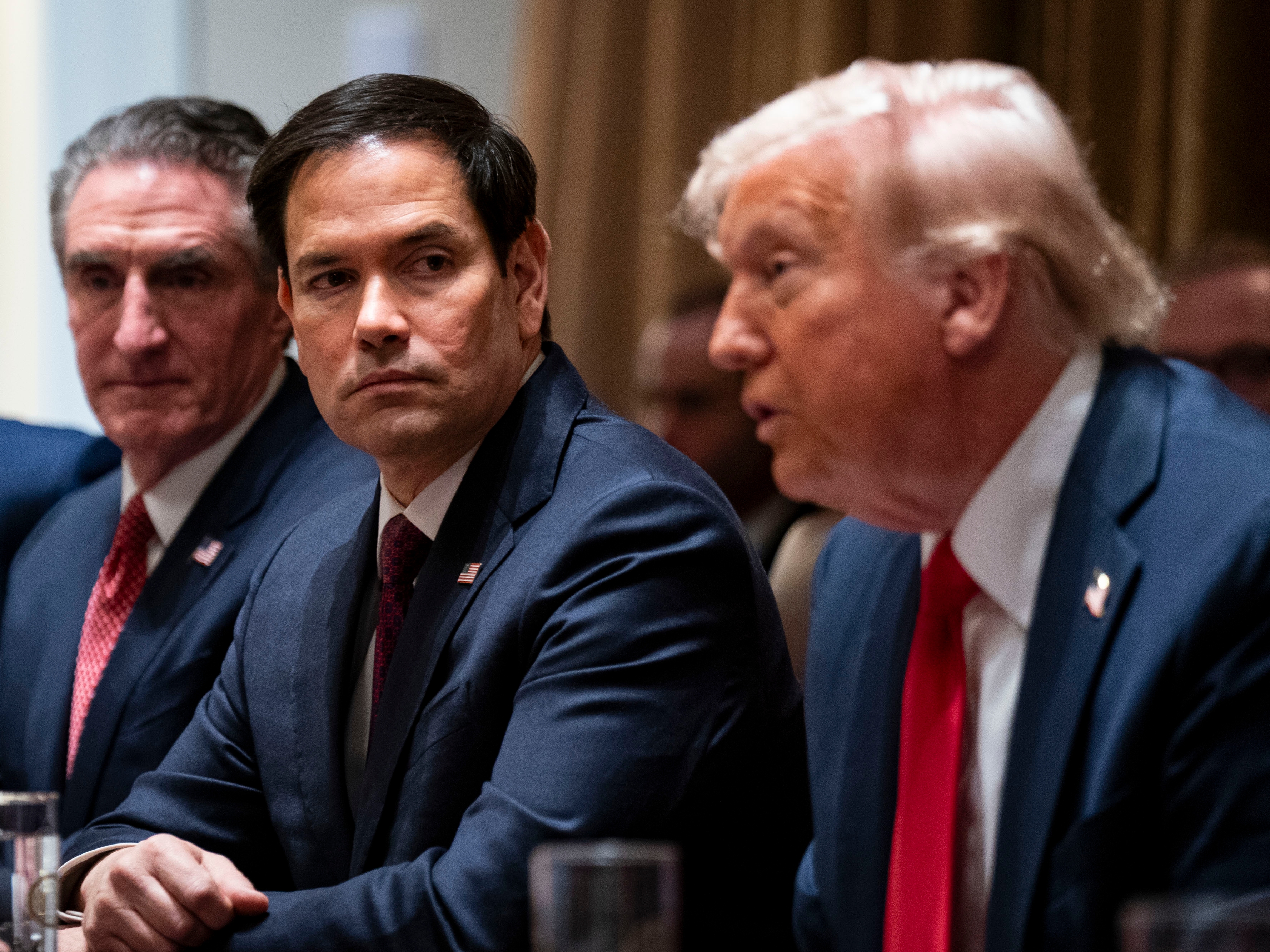 caption: Secretary of State Rubio (center) flanked by Doug Burgum, secretary of the interior, and President Donald Trump during a cabinet meeting on Feb. 26. On Monday, Rubio posted on X that 83% of USAID contracts had been canceled following a review.