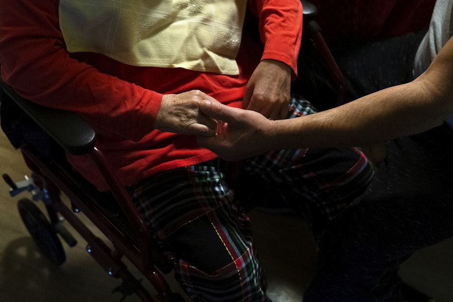 caption: Omar, right, cares for his wife Marta, at their apartment on Tuesday, September 26, 2023, in Everett.