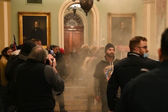 caption: Supporters of U.S. President Donald Trump storm the U.S. Capitol as smoke fills the corridor on January 6, 2021, in Washington, DC.