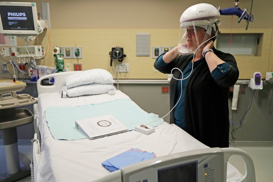 caption: Robin Addison, a nurse at Providence Regional Medical Center in Everett, Wash., demonstrated how she wears a respirator helmet with a face shield. 
