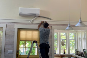 caption: CM Heating technician Hunter Morgan installs an HFC-using heat pump in a house in Shoreline, Washington, in July 2023.