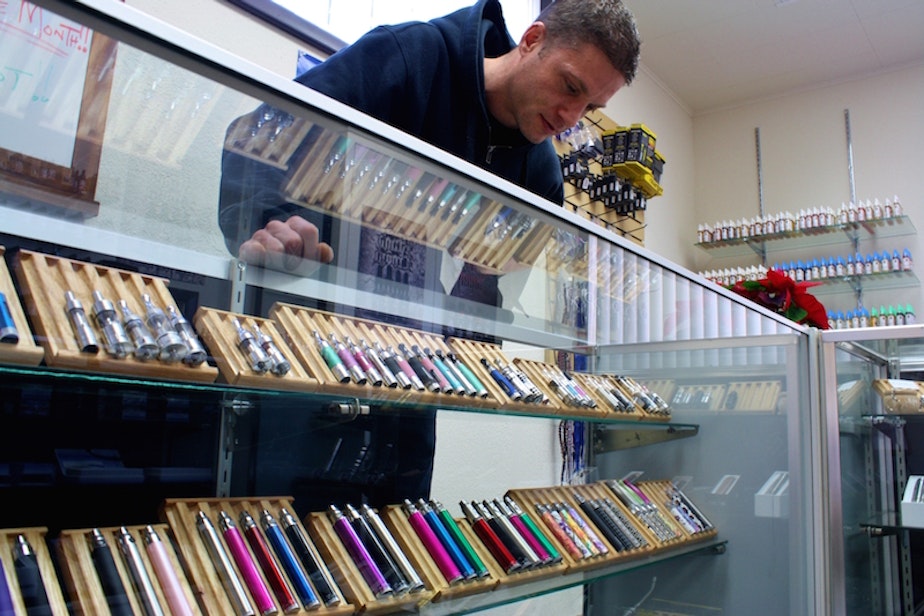 caption: In this file video, the owner of a Spokane electronic cigarette store examines his display case.
