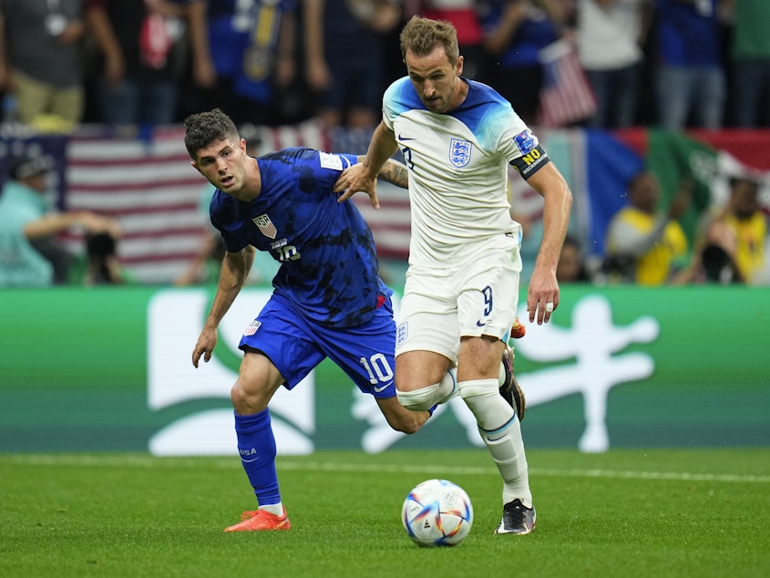 caption: England's Harry Kane, right, fights for the ball against Christian Pulisic of the United States during the World Cup group B soccer match at the Al Bayt Stadium in Al Khor, Qatar, on Friday.