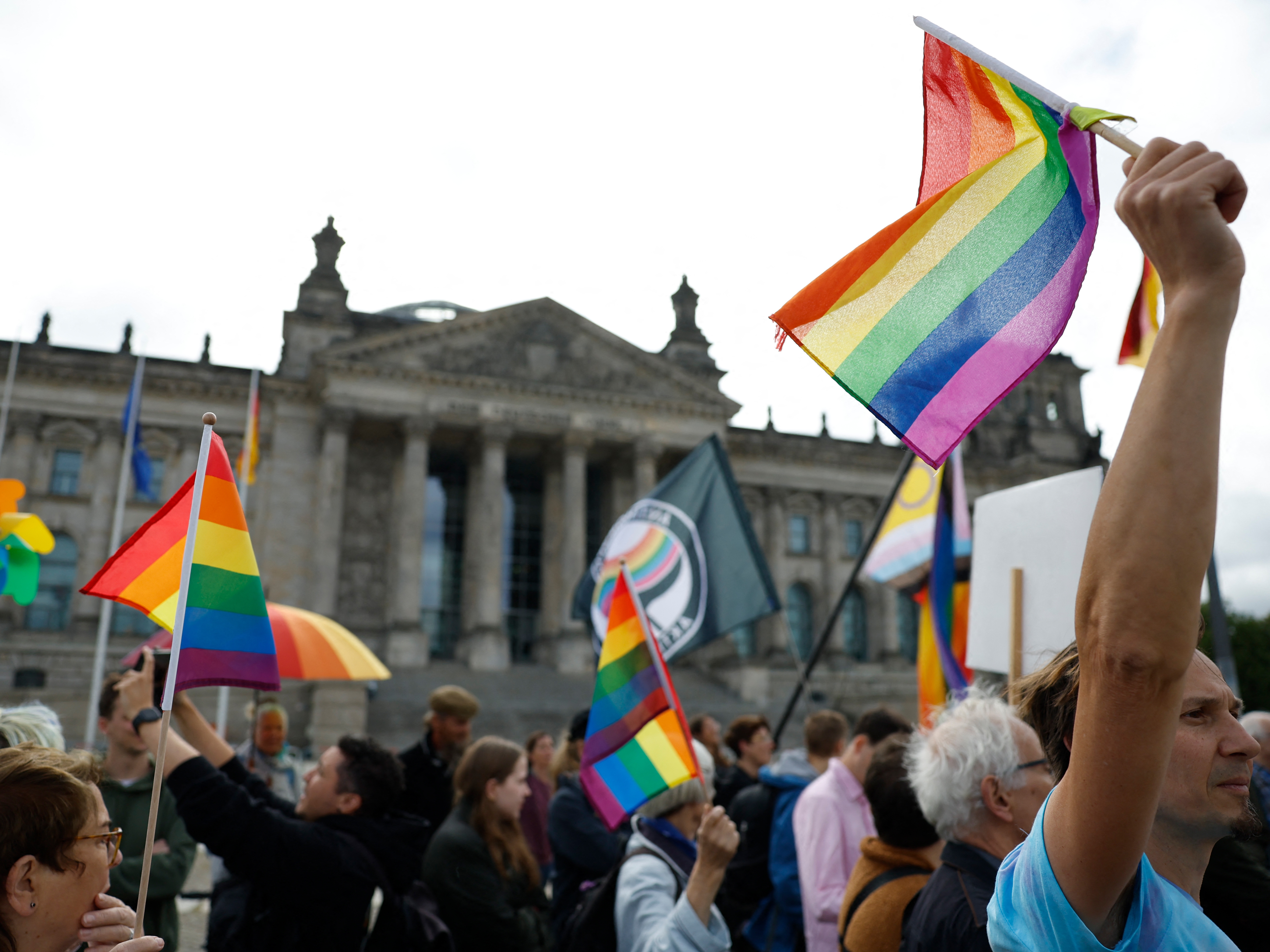 caption: Demonstrators participate in an event called "Show the flag: For queer visibility in the Bundestag!" in front of the Reichstag building that houses Germany's lower house of parliament, the Bundestag, in Berlin, on July 8. The conservative president of the Bundestag said the rainbow flag would no longer be raised on top of the parliament building during Pride month, which in Germany runs from June 28 until July 27.