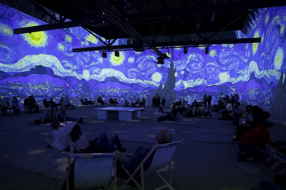 caption: Patrons take in 'Starry Night' as various projections of Van Gogh's work are displayed in the 360-degree 8,000-square-foot immersive room on Wednesday, October 27, 2021, at the exhibit in Seattle's SODO neighborhood.