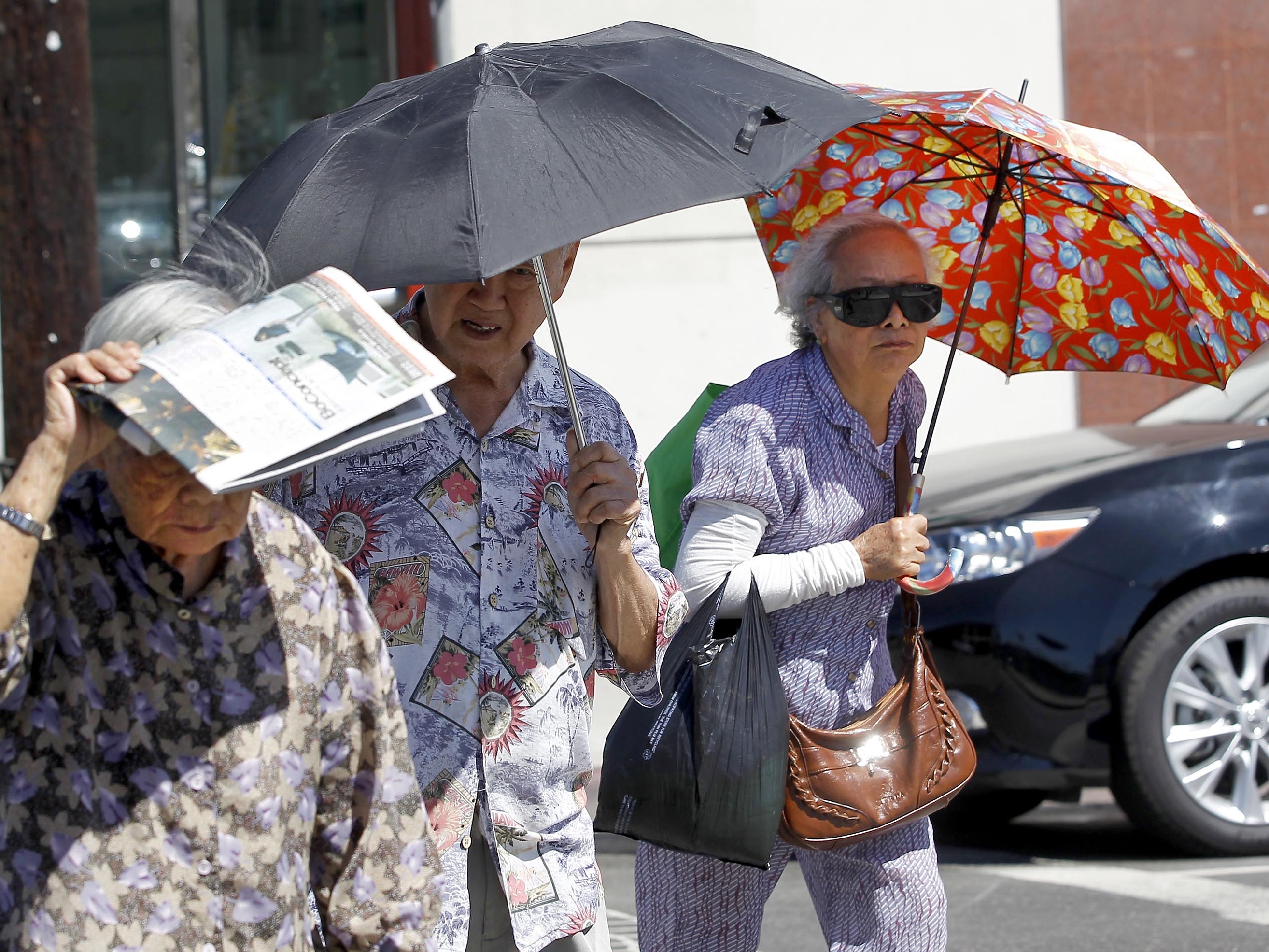 caption: Older people in Los Angeles' Chinatown neighborhood shade themselves from the sun. Exposure to heat can change the way people's genes work, potentially leading to long-term health impacts. Climate change is making heat waves more intense and last longer in many parts of the U.S.