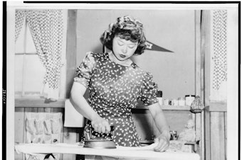 caption: Caption by photographer Dorothea Lange: Ester Naite, an office worker from Los Angeles, operates an electric iron in her quarters at Manzanar, California, a War Relocation Authority center where evacuees of Japanese ancestry will spend the duration. 