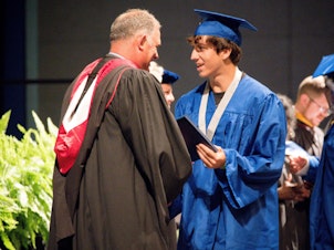 caption: Matanzas High School Principal Jeff Reaves shakes a student's hand on graduation day. Reaves handwrote 459 notes to the graduating class of 2021 to celebrate their accomplishments.