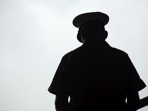 caption: Silhouette of a United States Marine praying, photographed from behind.