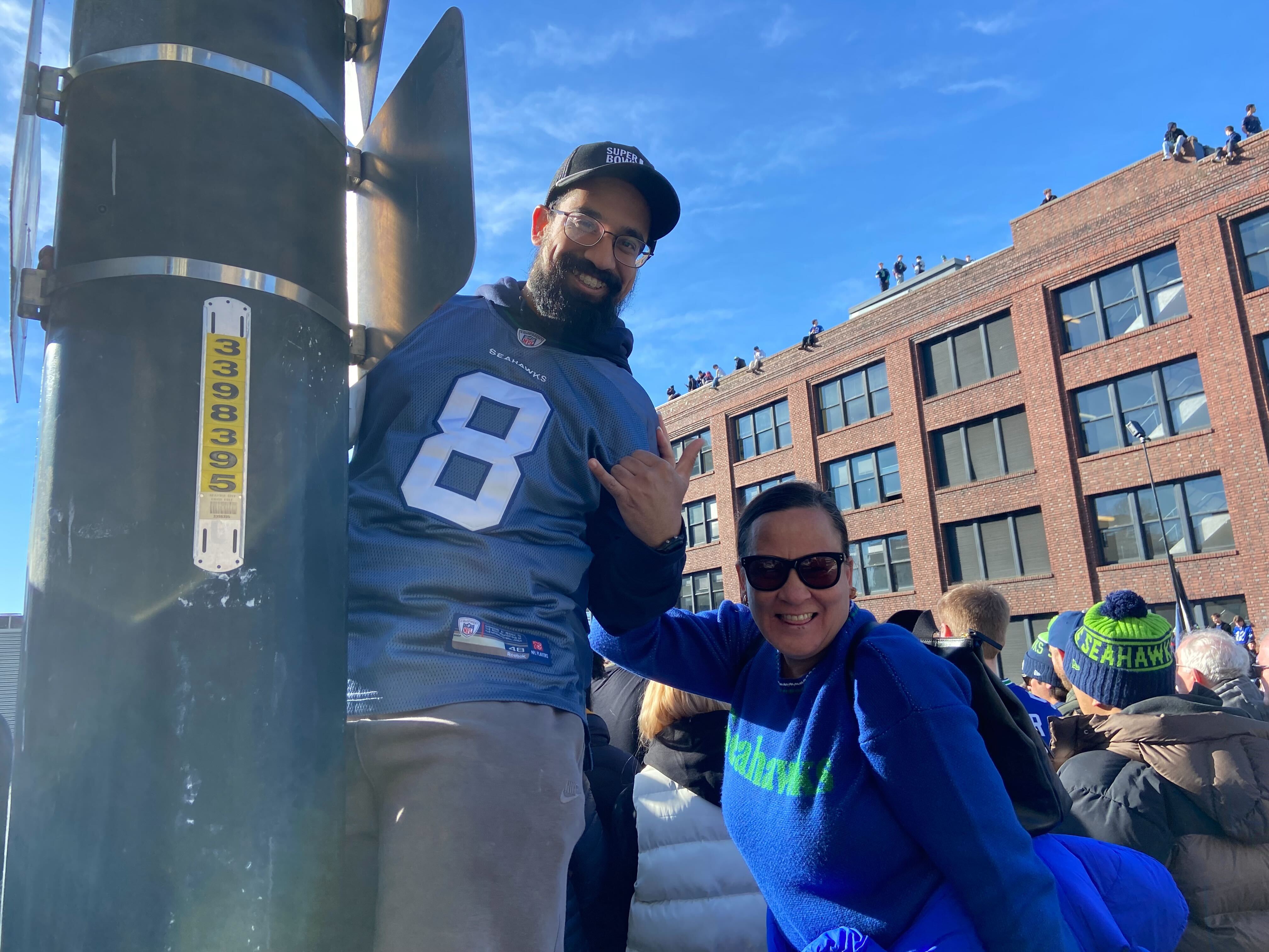 caption: Seattle Seahawks fans Rahul Prasad and Destiny Linayao pause their partying to take a photo during the Super Bowl LX parade on Wednesday, February 11, 2026. Prasad came all the way from Ohio to attend the game in California, then decided to drive to Seattle when the Seahawks won.