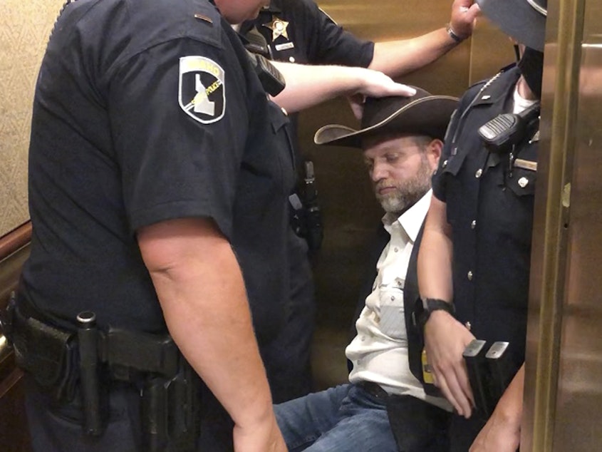 caption: After he refused to stand when asked, anti-government activist Ammon Bundy was wheeled into an elevator in a chair, following his arrest at the Idaho Statehouse in Boise on Tuesday.