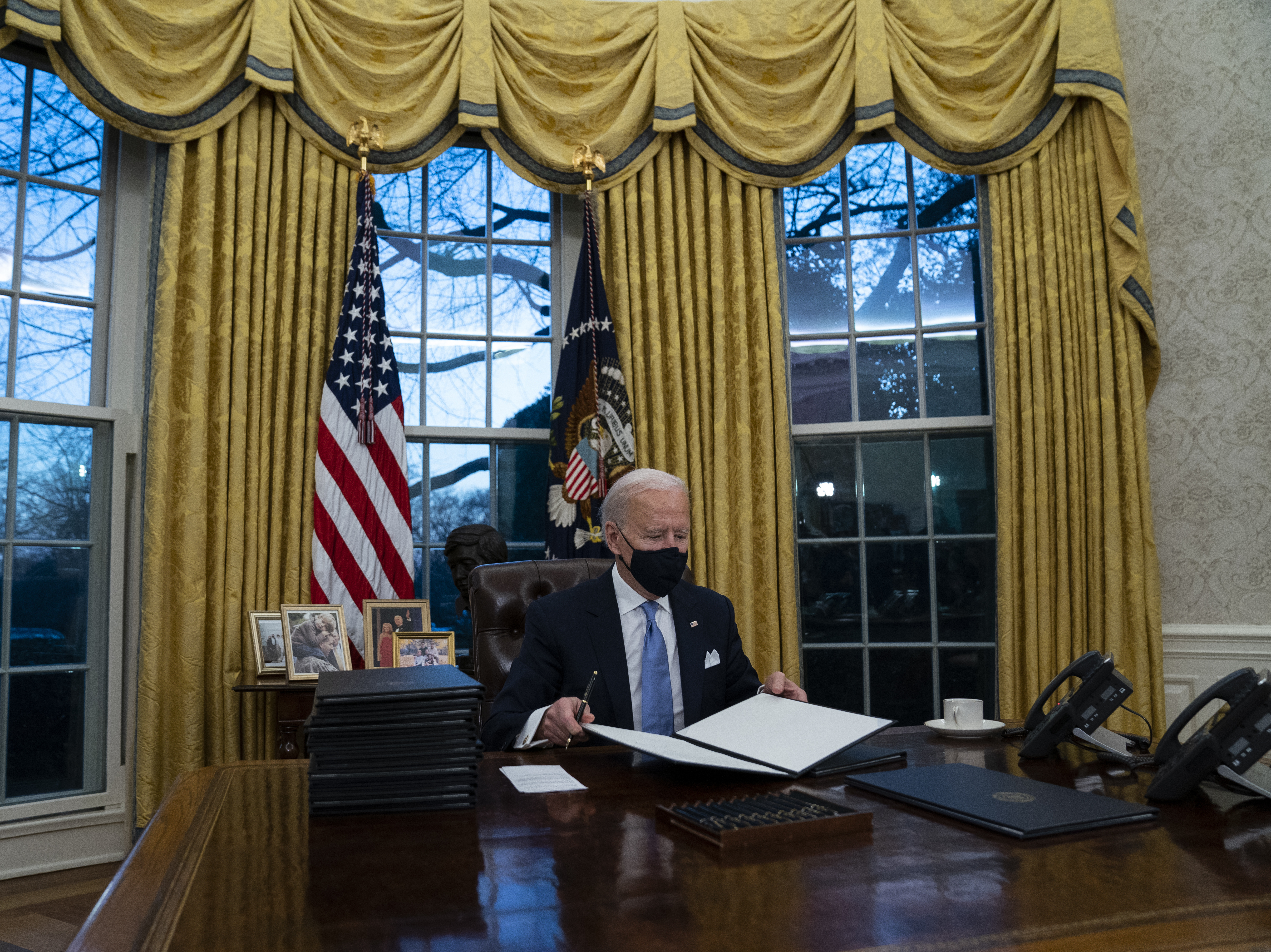 caption: President Biden signs executive actions hours after his inauguration on Wednesday. He is expected to reverse several Trump-era policies.